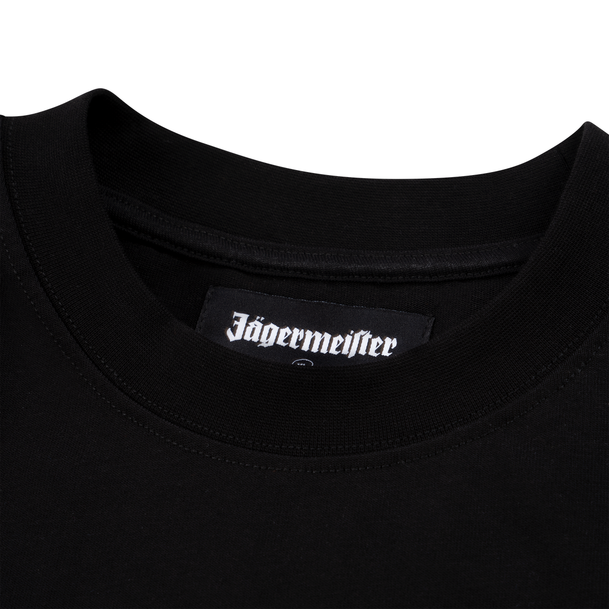 Prim-plan pe gulerul unui tricou negru Jägermeister, cu o etichetă țesută cu logo-ul Jägermeister la interiorul decolteului.