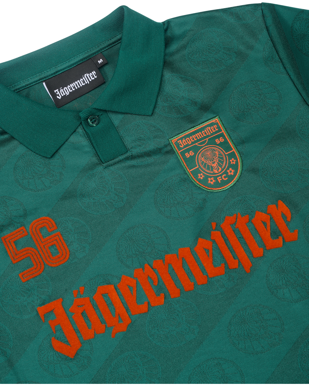 Prim-plan al unui tricou verde cu branding Jägermeister.
