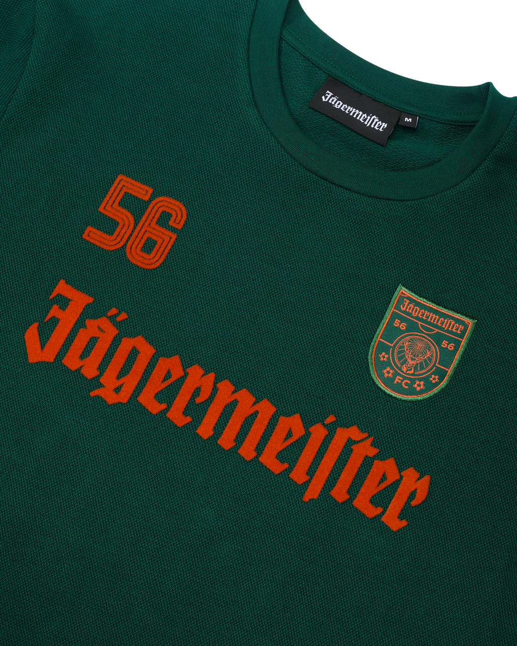 Bluză cu mânecă lungă verde Jägermeister, cu logoul Jägermeister portocaliu și un „56”.