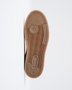A top-down view of a brown rubber shoe sole, showing the tread pattern and the embossed logos of Jägermeister and Flowers for Society